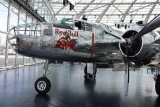 A historic B-25 Mitchell bomber in polished silver, proudly displayed in Red Bull’s Hangar-7.