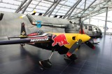 A Red Bull aerobatic aircraft and historic helicopter displayed inside the spectacular Hangar-7.